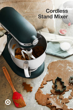 an image of a mixer with ginger cookies on the counter and cookie cutters next to it