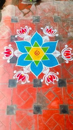 a colorful flower painted on the ground in front of a potted plant