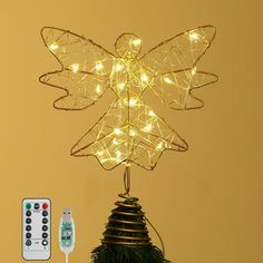 a christmas tree topper with fairy lights and remotes on it next to a wall