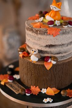 a three tiered cake with frosting and decorations on the top is decorated with fall leaves