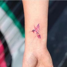 a small tattoo on the wrist of a woman's hand with a hummingbird