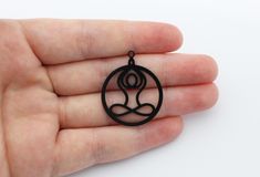 a hand holding a small black pendant in it's palm