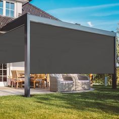 an outdoor covered patio area with chairs and table in the grass next to a house