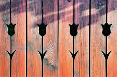 the wooden fence is painted orange and has black flowers on it's sides,