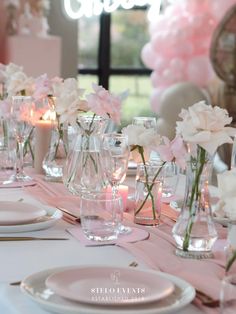 the table is set for a party with pink and white flowers in vases on it