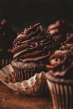 three chocolate cupcakes sitting on top of a wooden table next to each other