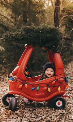 a small child is sitting in a red car with christmas lights on the front and sides