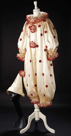 an old fashioned dress with red and white polka dots on it, sitting on a mannequin