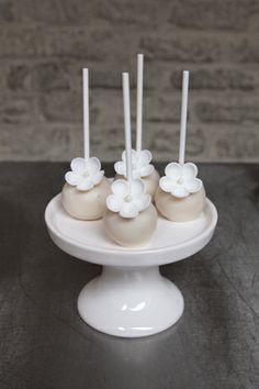 there are four cake pops with flowers on the top and two candles in the middle