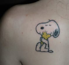 a person with a small tattoo on the back of their shoulder that has a cartoon character holding a star