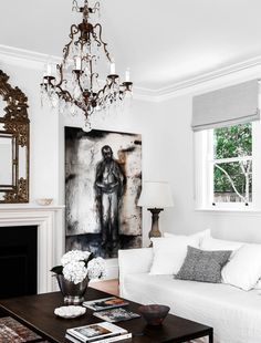 a living room filled with furniture and a chandelier hanging from the ceiling over a fire place