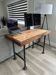 a wooden table with two laptops on it in front of a gray couch and window