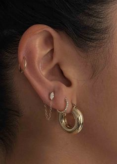 a woman's ear with two gold hoops and one diamond on the side