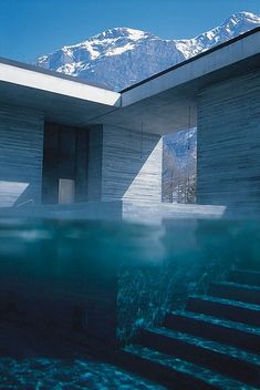 an underwater view of a building with mountains in the background