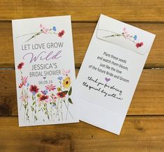 two wedding cards with flowers on them sitting next to each other in front of a wooden background