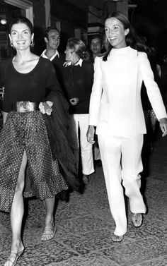 black and white photograph of two women walking down the street with other people behind them