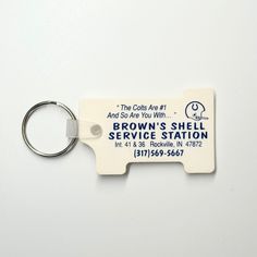 a white key chain with a brown's shell service station logo on it