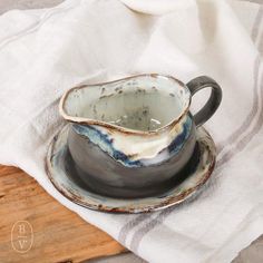 a cup and saucer sitting on top of a wooden cutting board next to a white towel