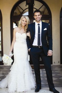 a bride and groom posing for a photo in front of the entrance to their wedding venue