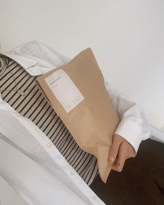 a person holding a brown paper bag in their hand and wearing a white shirt with black stripes