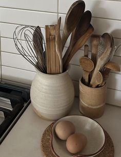 two bowls with spoons and wooden utensils in them on a kitchen counter