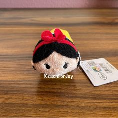 a small stuffed doll with a red bow on it's head sitting on a wooden table