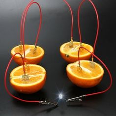 four oranges with wires attached to them on a black surface and one is cut in half