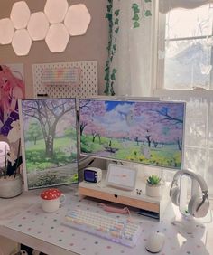 two computer screens sitting on top of a desk next to a keyboard and headphones