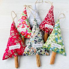 four small christmas trees are hanging from clothes pins with name tags on them and decorated with flowers