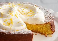 a piece of cake with icing and lemon zest is on a white plate