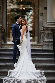 a bride and groom standing on the steps in front of a building