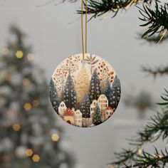 a christmas ornament hanging from a tree with lights in the background and a small town on it