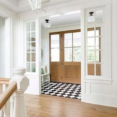 an entryway with a checkered floor and wooden door in the center is shown