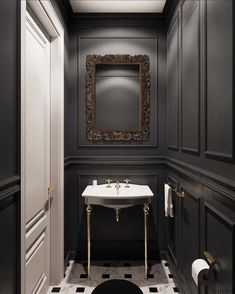 a bathroom with black and white tile flooring and walls, along with an ornate framed mirror above the sink