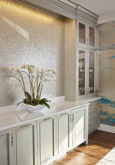 a vase with some flowers in it sitting on a counter top next to cabinets and cupboards