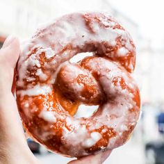 a hand holding a glazed donut with icing