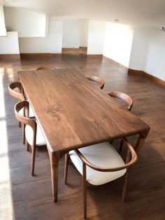 a large wooden table sitting in the middle of a room with white chairs around it