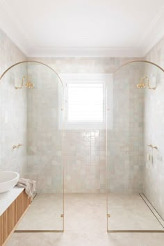 a bathroom with a walk in shower next to a white sink and mirror on the wall