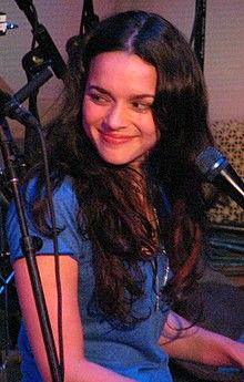 a woman sitting at a keyboard in front of a microphone