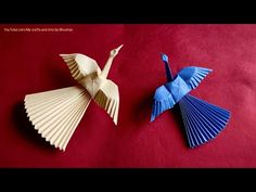 two origami cranes sitting on top of a red surface