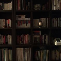 a bookshelf filled with lots of books in a dark room