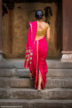 a woman in a pink sari walking up some steps with her back to the camera