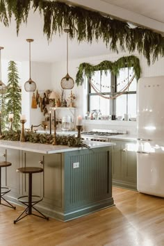 the kitchen is decorated for christmas with greenery on the counter and lights hanging from the ceiling