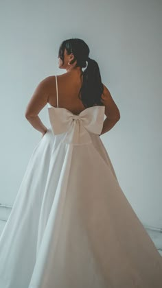 a woman in a white dress is standing with her back to the camera