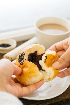 a person holding a half eaten doughnut on a plate next to a cup of coffee