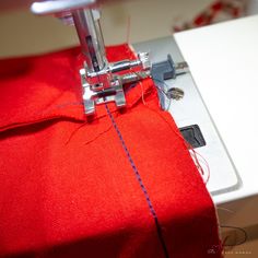 the sewing machine is working on the red fabric