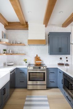 a kitchen with blue cabinets and white counter tops, wooden beams above the stove top