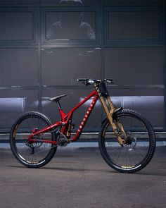 a red and gold bike parked in front of a building with large doors behind it