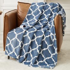 a blue and white blanket sitting on top of a brown leather chair in front of a fireplace