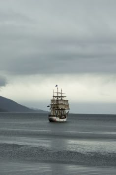 a large boat floating on top of a body of water under a gray cloudy sky